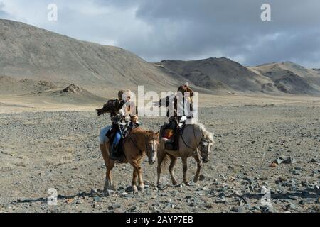 A Kazakh father and daughter eagle hunter in the Sagsai Valley in the Altai Mountains on the way to the annual Golden Eagle Festival near the city of Stock Photo