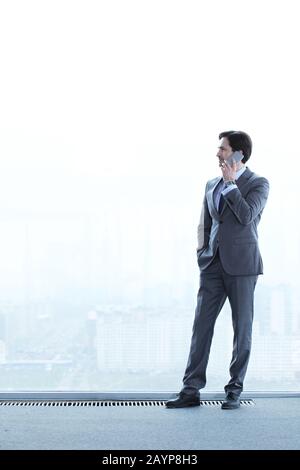 Business man talking on phone standing near office window Stock Photo