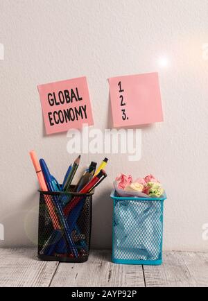 Writing note showing Global Economy. Business concept for Worldwide economic activity between various countries Two Pink Sticky Notes on Wall Pencil P Stock Photo