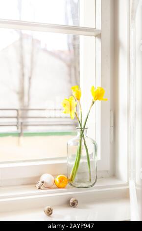 minimalistic easter decoration on windowsill easter bells, daffodils in old building easter eggs on windowsill light background, with copy space Stock Photo