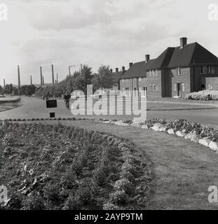 1950s, historical, an industrial worker cycling along a road at the housing estate outside of the London Brick Company, at the Stewartby brickworks, Bedford, England, UK. The company was a paternal employer in the mould of the victorian and quakers of the previous century and provided their workers with solid brick-built housing and extensive leisure facilities in a so-called 'model village'. Stock Photo