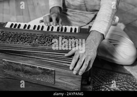 Closeup of senior male shamanic hands playing indian musical instrument harmonium as sacred and kirtan music for peaceful meditation Stock Photo