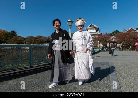A wedding couple in traditional clothing is posing in front of the castle at the Kanazawa Castle Park in Kanazawa, Ishikawa Prefecture, on Honshu Isla Stock Photo