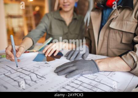 Close up of young woman looking at floor plans with building contractor while while discussing home renovations, copy space Stock Photo