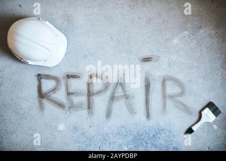 Background image of REPAIR word on concrete floor with building tools in house under construction, copy space