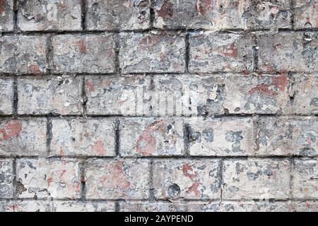 Old brick wall texture, vintage background. Weathered facade of a building with white peeled paint Stock Photo