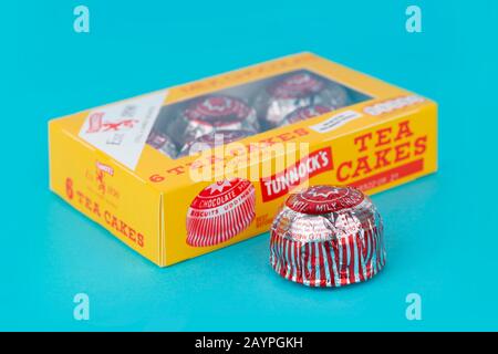 A Tunnock's milk chocolate tea cake shot on a blue background along with the product's box packaging. Stock Photo