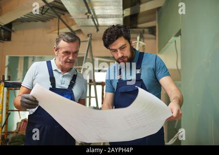 Portrait of father and son looking at floor plans while renovating house together, copy space Stock Photo
