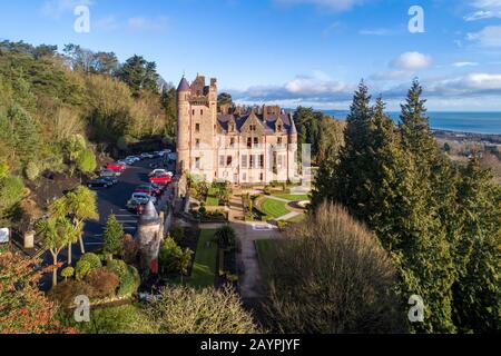 Belfast castle. Built in 19th  Tourist attraction on the slopes of Cave Hill Country Park in Belfast, Northern Ireland. Aerial view. Belfast Lough in Stock Photo