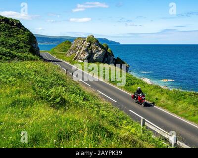 The eastern coast of Northern Ireland and Antrim Coast Road A2, a.k.a Causeway Coastal Route with a motorcycle. One of the most scenic coastal roads