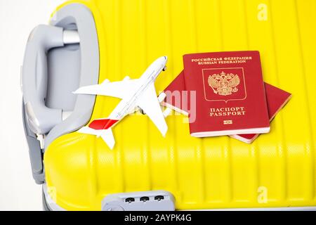 Airplane toy with two Russian Federation passports on a yellow suitcase. Travel and airport custom concept Stock Photo