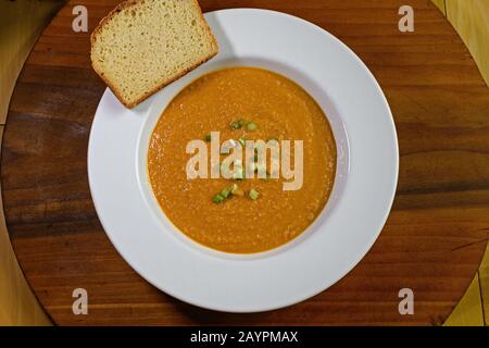 Vegetarian, gluten free peanut soup or groundnut soup in bowl with slice of gluten free bread. It is made from peanuts, carrots, sweet potatoes and sc Stock Photo