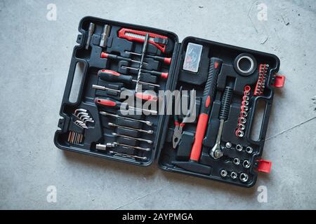 Top view background of open tool box with red hammer and screwdriver on concrete floor at construction site, copy space Stock Photo