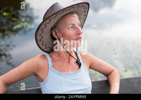 A woman in a cowboy hat, in nature. Near water. Stock Photo