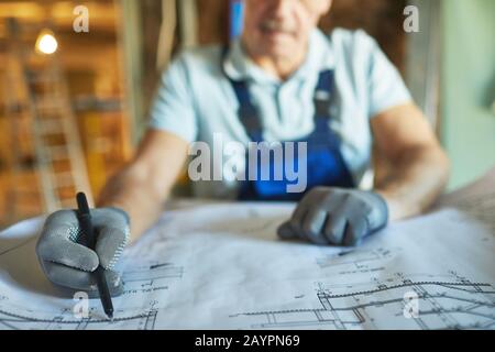 Close up of senior construction worker looking at floor plans while renovating house, copy space Stock Photo