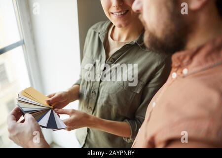 Close up of happy couple looking at color samples standing by window while redecorating house, copy space Stock Photo