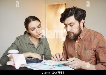 Portrait of married couple budgeting redecorations cost while sitting at table in empty room Stock Photo