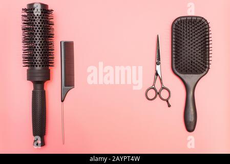 Flat lay composition with hairdresser set on pink background. Barber set with tools and equipment: scissors, combs and hairclips with copy space for text. Stock Photo