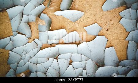 background old pieces of blue cracked and peeling paint on a brown wall Stock Photo
