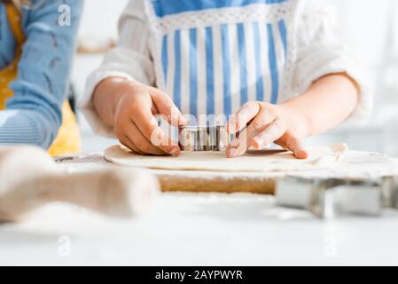 selective focus of kid using dough mold on dough in kitchen Stock Photo