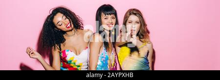 panoramic shot of emotional fashionable multiethnic girlfriends dancing on pink Stock Photo