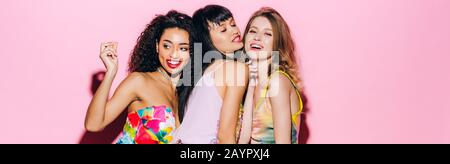 panoramic shot of happy fashionable multiethnic girlfriends dancing on pink Stock Photo