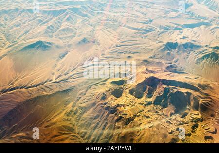 looking down onto eroded deset landcape in Chile from the air with a large mine. Stock Photo