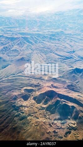 looking down onto eroded deset landcape in Chile from the air with a large mine. Stock Photo