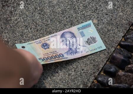 Close up of picking up a five hundred thousand dong money note on the floor Stock Photo