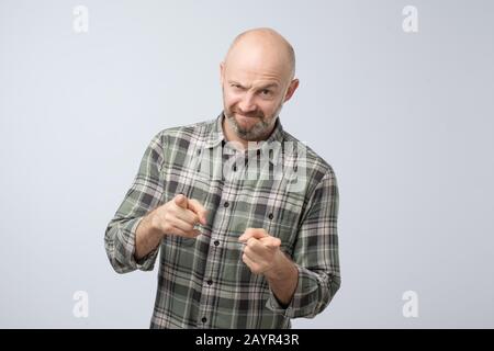 Angry attractive mature man pointing a finger towards you. I blame you in all my problems. Studio shot Stock Photo