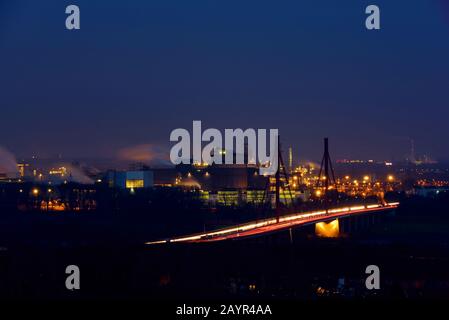 view from stuck pile Rheinpreussen to iron and steel industry of ThyssenKrupp and motorway A42 bridge in the evening, Germany, North Rhine-Westphalia, Ruhr Area, Duisburg Stock Photo
