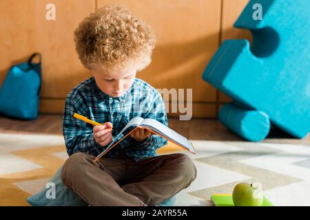 smart child looking at notebook and holding pen Stock Photo