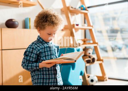 curly and smart child reading book at home Stock Photo