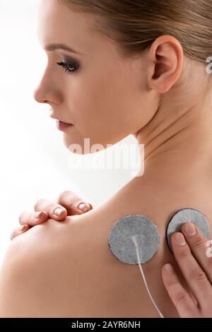 Doctor fastening electrode on back of beautiful woman isolated on white Stock Photo