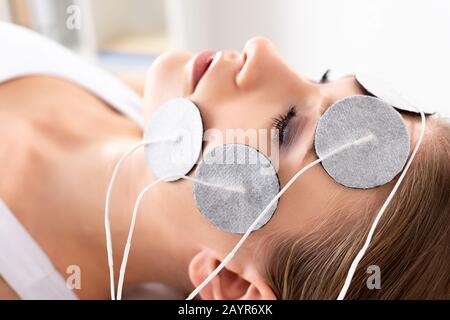 Side view of beautiful woman with electrodes on face during electrode treatment in clinic Stock Photo
