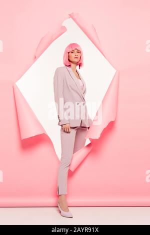 fashionable beautiful girl in suit and pink wig posing in torn paper, on white Stock Photo