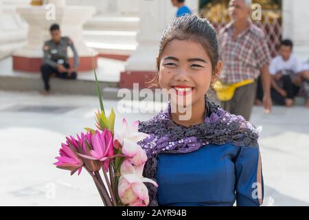 A teenage girl with waterlily flowers for an offering (part of the prayer ritual) at the 2,500 years old Shwedagon Pagoda in Yangon (Rangoon), the lar Stock Photo