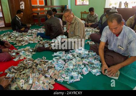 Men counting money donated to at the Gubyaukgyi Temple, Bagan, Myanmar. Stock Photo