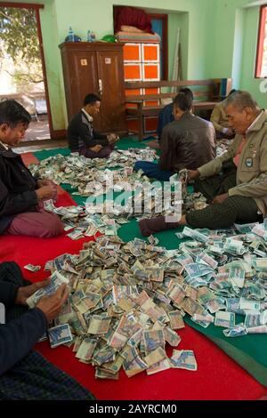 Men counting money donated to at the Gubyaukgyi Temple, Bagan, Myanmar. Stock Photo