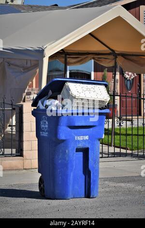Trash and cans and dumpster for pickup by recycling and disposal company to take to landfill for value of items in cans Stock Photo