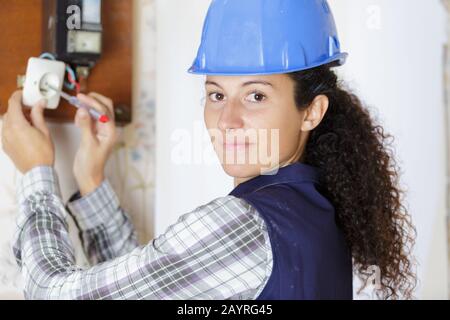 female electrician fixing electric cables in socket Stock Photo