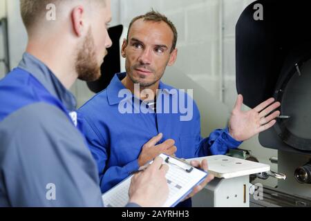 two workers wearing protective uniform talking in factory Stock Photo