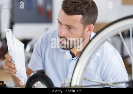 handyman reading manual while fixing bike Stock Photo