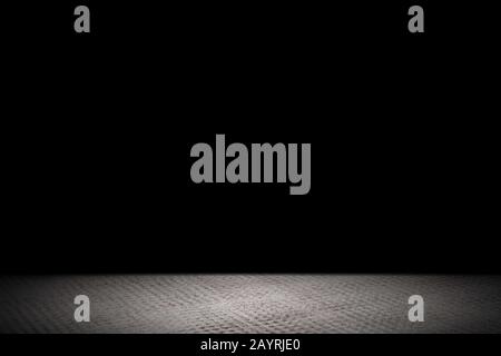 Light shining down on rough gray concrete floor in dark room with copy space, abstract background Stock Photo