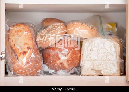 Variety of breads stored in plastic bags in cupboard in kitchen Stock Photo