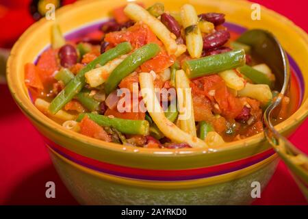 Herbed three-bean dish with tomatoes in a bowl, containing green beans, yellow wax beans and kidney beans