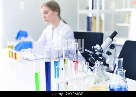 Young female scientist doing some research working conduct experiments and microscope in modern laboratory / Scientists in lab biochemistry genetics f Stock Photo