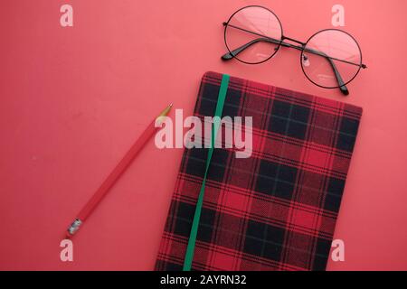 top view of red color notepad, pencil and eyeglass  Stock Photo