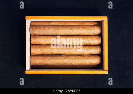 Close up of cigars in open humidor box on black table in the dark. Stock Photo