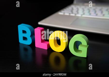 The word blog on a black table against a gray laptop. The concept of video blogging development in the world. Stock Photo